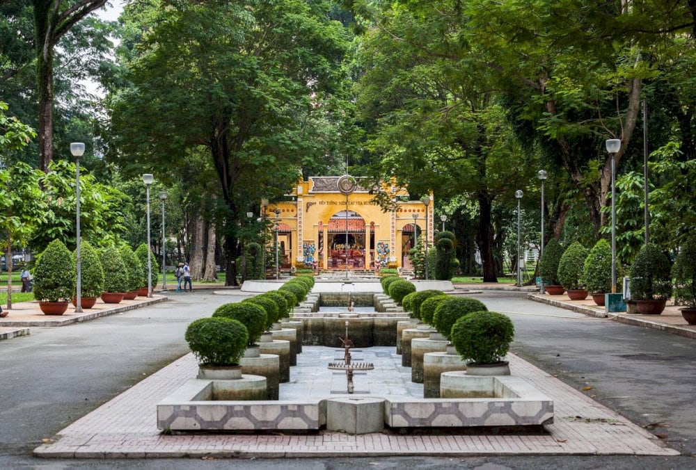 Tree-lined path in Tao Dan Park, where locals stroll or exercise, surrounded by calm, refreshing greenery in the middle of the city